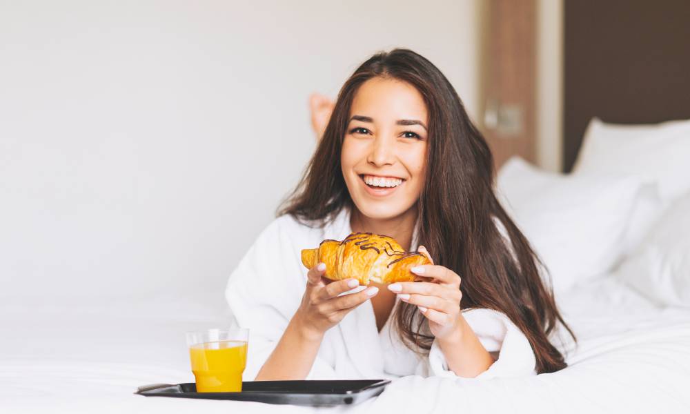 Brünette Frau mit Croissant im Bett